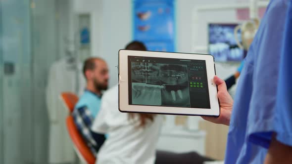 Close Up Dentist Nurse Holding Tablet with Digital Radiography