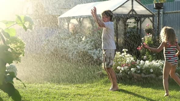 children play fun under the spray of water on the lawn of the house