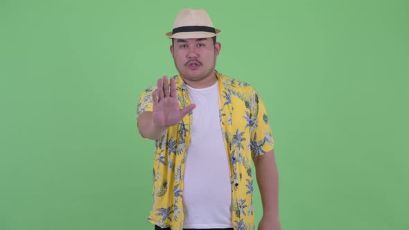 Serious Young Overweight Asian Tourist Man with Stop Gesture