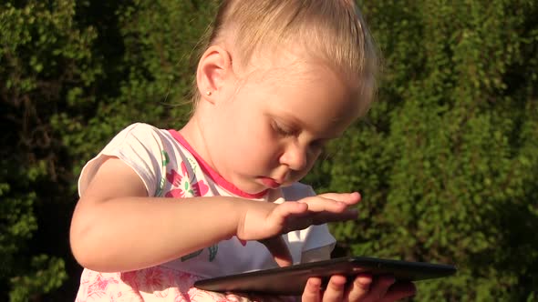 Cute Happy Little Girl Holding a Tablet