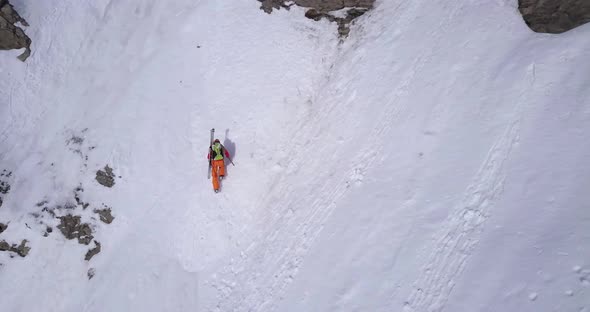 Aerial drone view of a mountain climber climbing up with crampons in the snow.