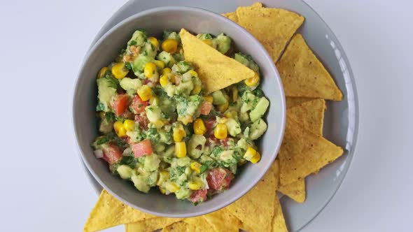 Avocado dip guacamole with grilled corn in gray bowl, top view.