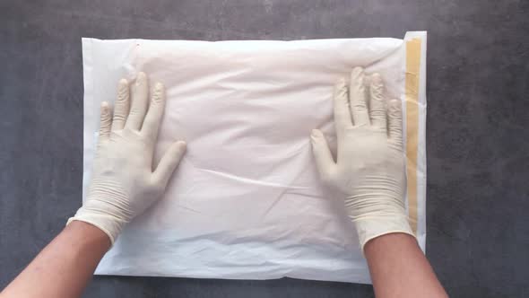 Hand in Latex Gloves Holding White Paper Bubble Envelope for Postal Ship