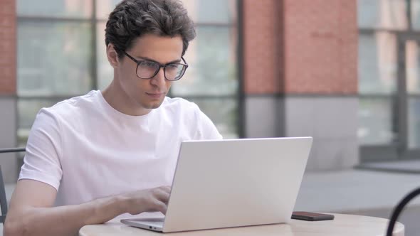 Young Man with Headache Working on Laptop Sitting Outdoor