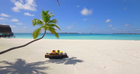 Aerial view of a couple lounging on a beach at a tropical island resort hotel.