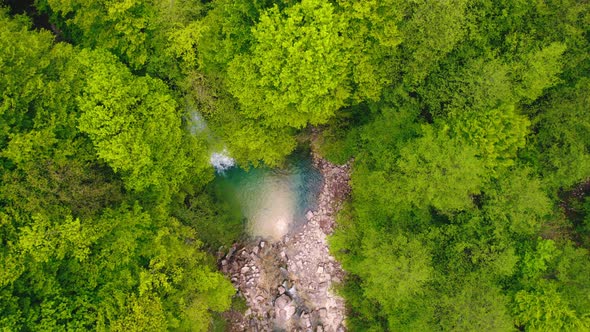 Ascending Shot of a Small Waterfall and Lake in the Green Forest Aerial