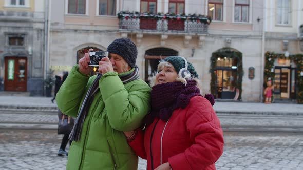 Grandfather Taking Photo Pictures with Grandmother on Retro Camera in Winter Snowy Town Lviv Ukraine