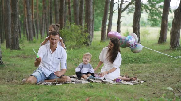 Happy family relax lying picnic blanket. Parents rest on grass with two kids