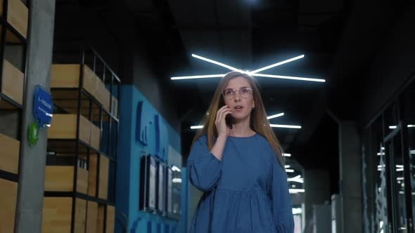 Successful businesswoman walks down corridor and calls on her mobile phone