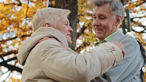 Loving Old Married Caucasian Couple Stand Outdoor in Autumn Park Hugging Old Mature Grandmother
