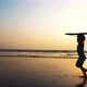 Little girl is running along the ocean sand beach with surfboard at sunset. - VideoHive Item for Sale