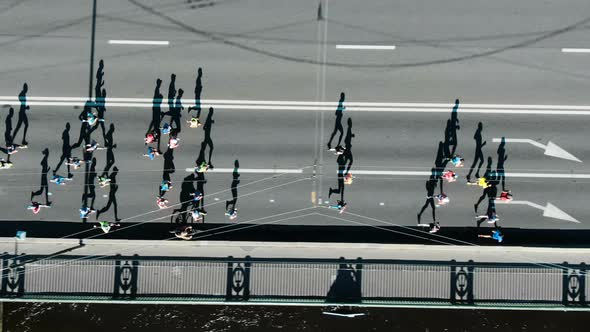 Aerial view of the city marathon, a crowd of people running through the distance, running shadows