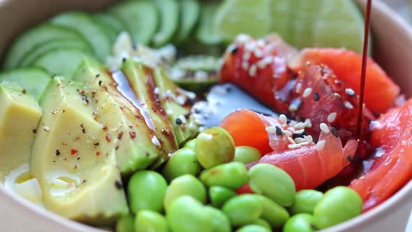 Pouring sauce on poke bowl