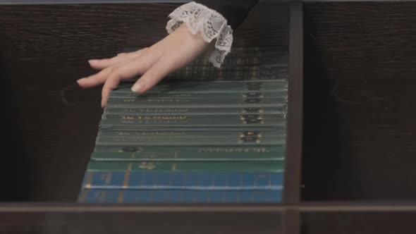 Hand of Female Takes Book From Bookshelf