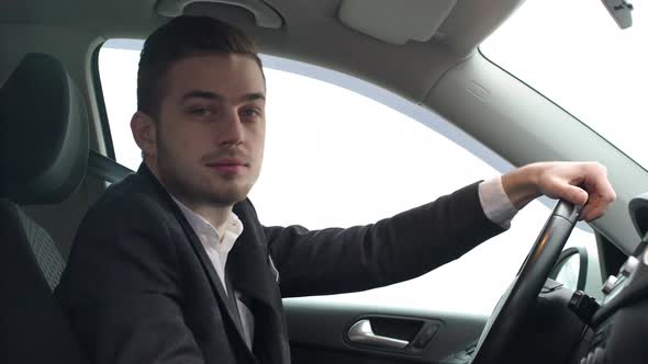 Portrait Closeup of Handsome Male Office Worker in Suit Smiling While Driving His Car on Road or