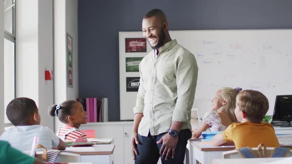 Video of happy african american male teacher during lesson with class of diverse pupils