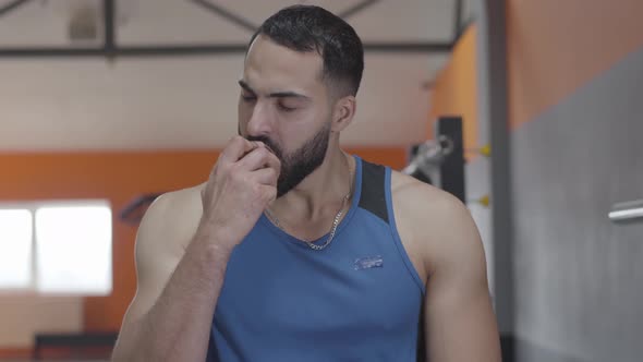 Close-up of Handsome Middle Eastern Sportsman with Brown Eyes Biting Red Apple and Chewing