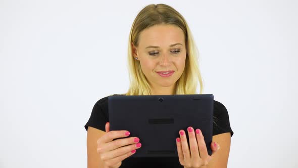 A Young Beautiful Woman Looks at a Tablet with a Smile - White Screen Studio