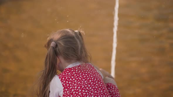 Little Blonde Girl Plays with Fountain Water in Urban Park