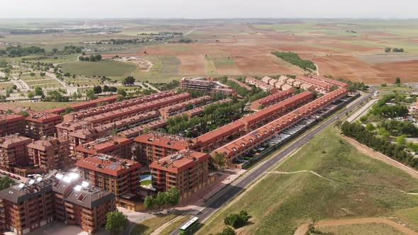 Modern living district in Spain with public bus speeding by, aerial zoom in view