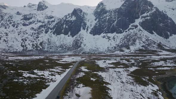 Empty road cutting through the snowy mountains in Grøtfjord. Kvaløya, northern Norway. 4K drone.