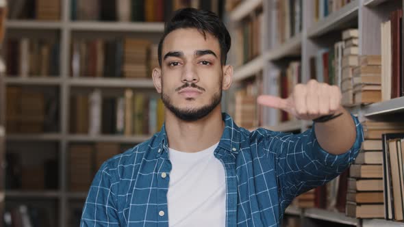 Portrait Displeased Young Hispanic Man Standing Indoors Thumb Down Showing Disapproval Gesture