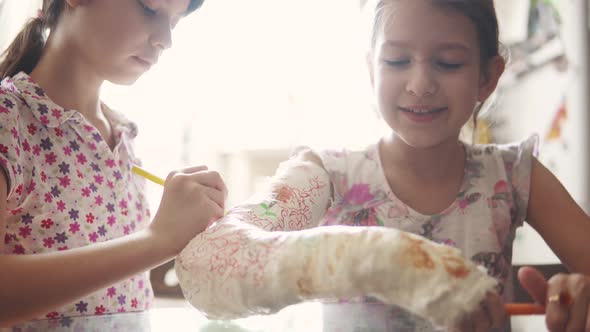 Child Draws on Plaster the Girl Paints a Plastered Hand To Her Sister