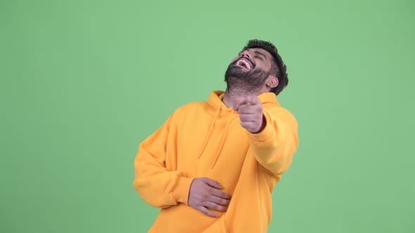 Happy Young Overweight Bearded Indian Man Laughing and Pointing at Camera