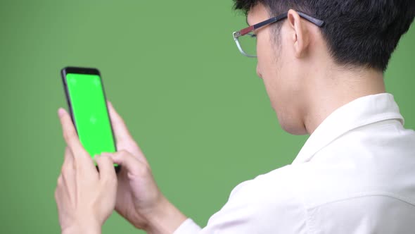 Young Asian Businessman Using Phone While Showing Copy Space
