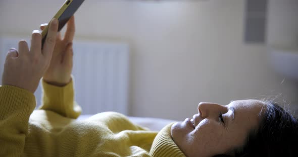 Authentic shot of woman on the bed listening to music and singing