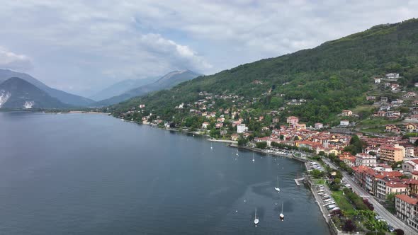 Aerial truck left shot of a village with red tile roof buildings ascending a hill along the shore of