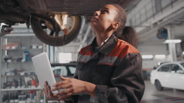Black Female Auto Mechanic Inspecting Car