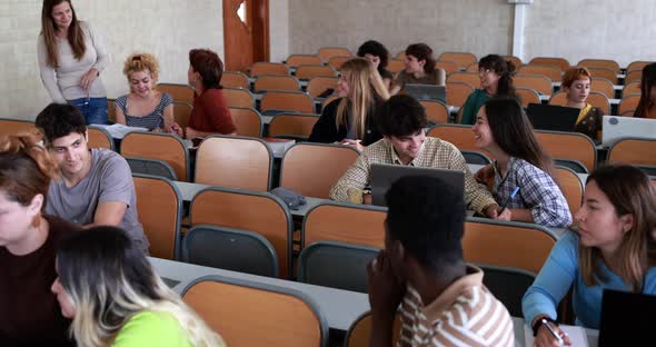 Mature teacher working with students inside classroom at school university