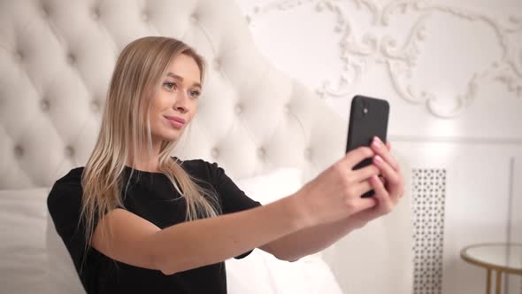 Woman Sits in Bed in Bedroom and Poses for Social Media App Videos Photos