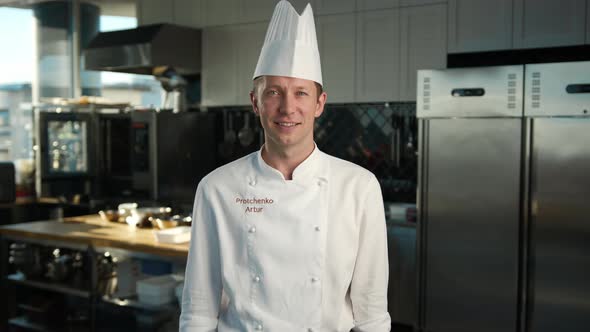 Professional kitchen portrait: Male Chef showing thumbs up and smiling