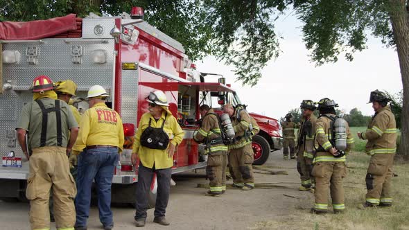 Firemen next to fire truck getting gear on