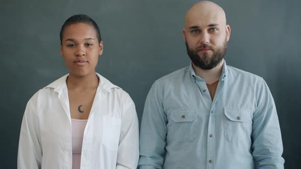 Portrait of Serious Young People AfroAmerican Girl and Caucasian Guy Standing on Gray Background