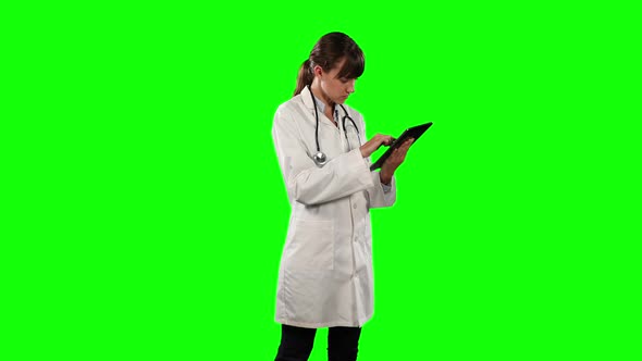 Side view of a female doctor using digital tablet with green screen