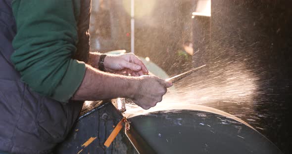 Bladesmith wet grinding a blade