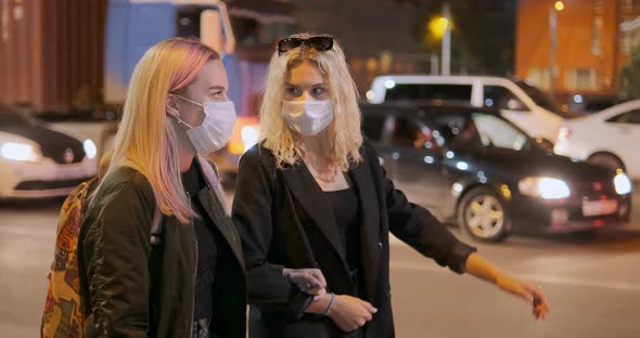 Young Women in Medical Masks Walk Along Night City Street