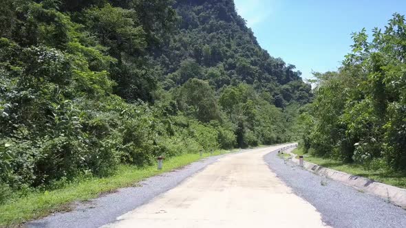 Exciting Jungle Road with Red and White Poles Against Hills