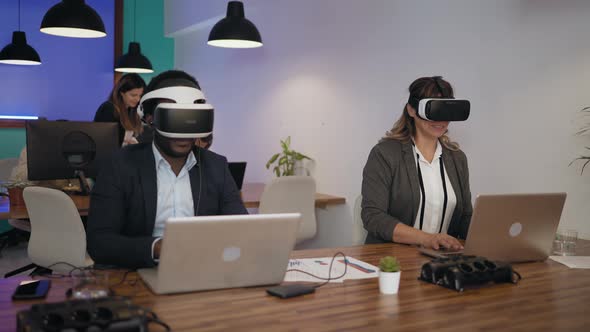 Business people wearing virtual reality glasses while working in modern creative space