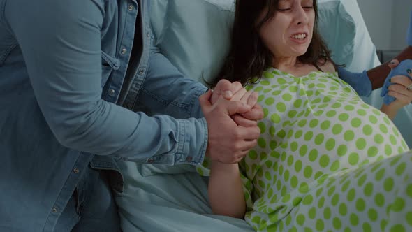Woman in Pain From Childbirth Holding Hands with Husband