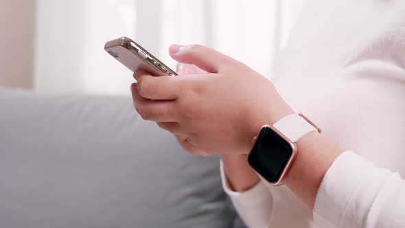 Close up of hand woman using smartphone and smartwatch in the living room for business and shopping