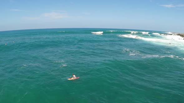 Aerial view of a man sitting while sup stand-up paddleboard surfing in Hawaii