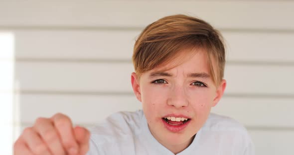 Portrait of blond boy knocking on invisible glass pane