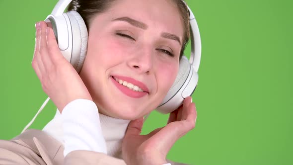 Girl Listens To Melodious Songs in the Headphones. Green Screen. Close Up