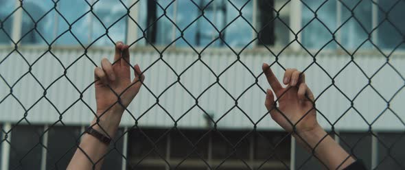 Female hands holding onto metal fence