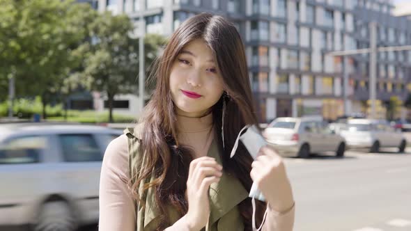 Young Asian Woman Takes Off Her Face Mask Looks Camera Street Urban Area