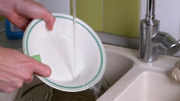 Male Hands Wash Dirty Plate in Kitchen Sink Under Running Water